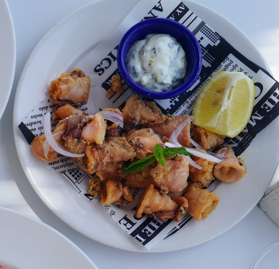 Plate of golden fried calamari with tartare sauce, red onion and lemon