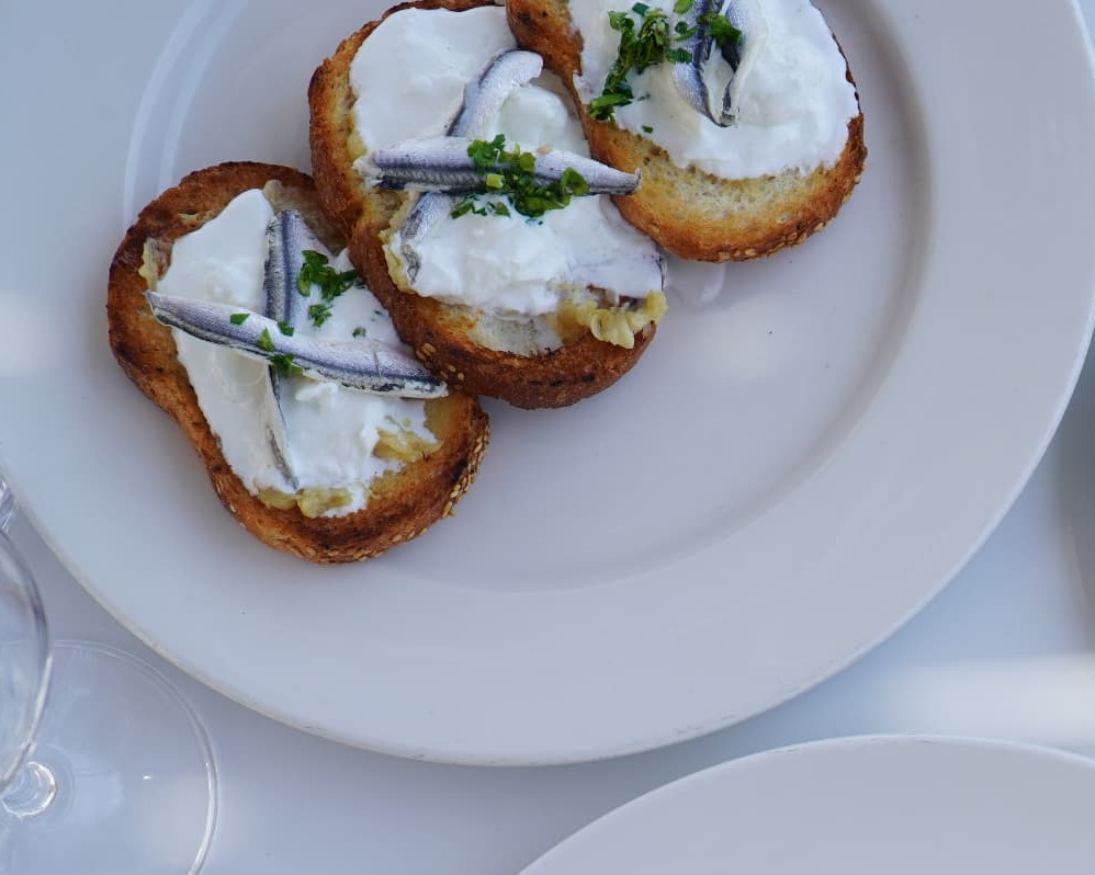 Toasted sourdough crostini with whipped cheese and marinated anchovies